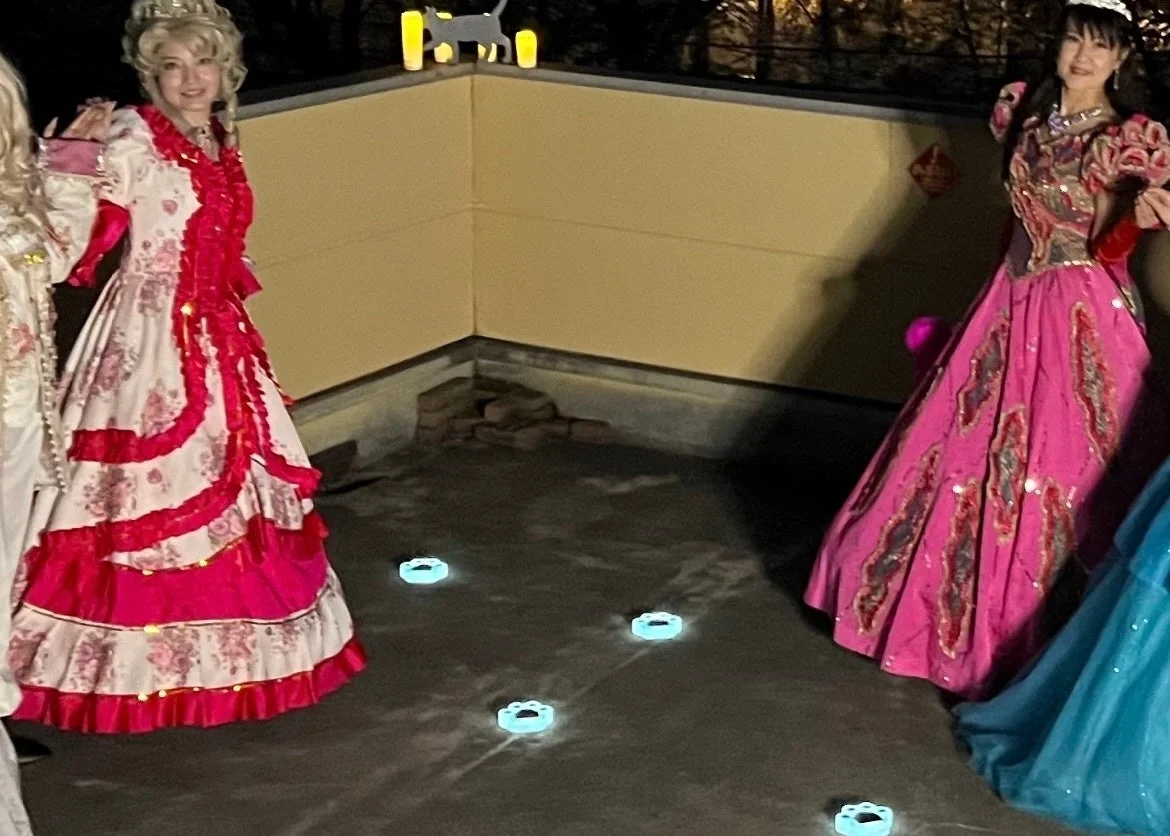 夜の屋外で煌びやかなドレスをまとった女性たちと光の装飾