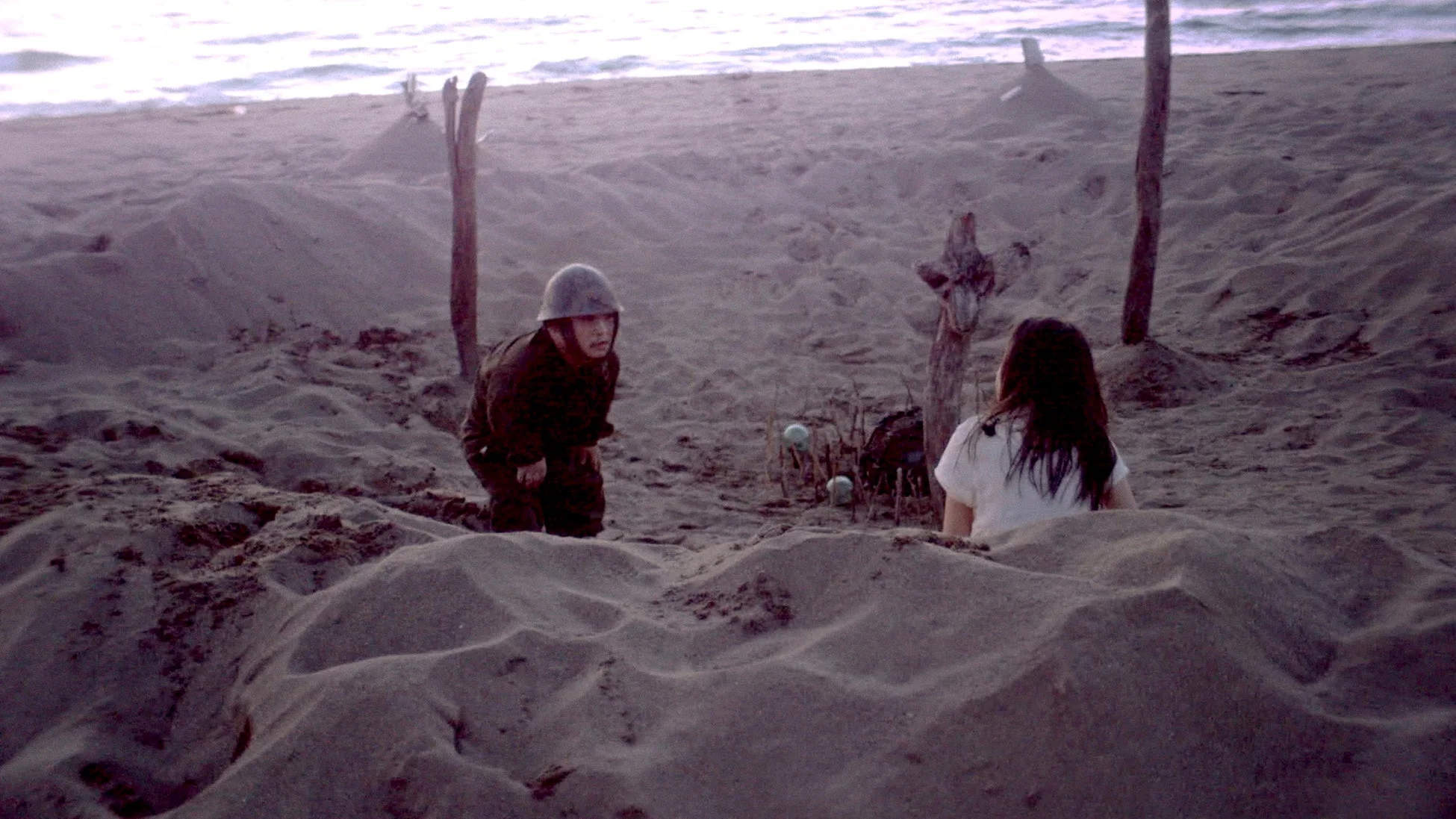 砂浜で兵士と女性が向かい合う