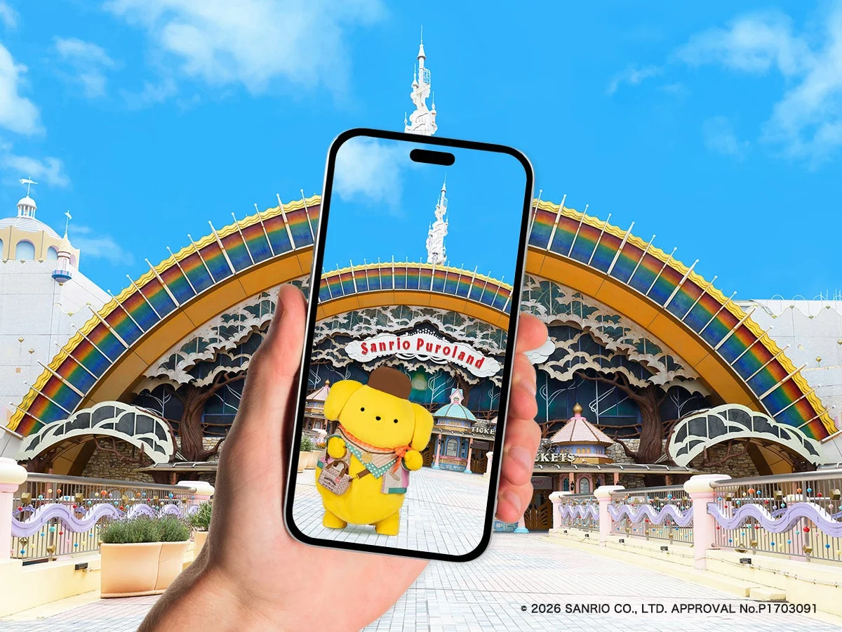 サンリオピューロランドのカラフルな虹のアーチがある入り口で、スマートフォンを通してポムポムプリンのAR体験をしている様子