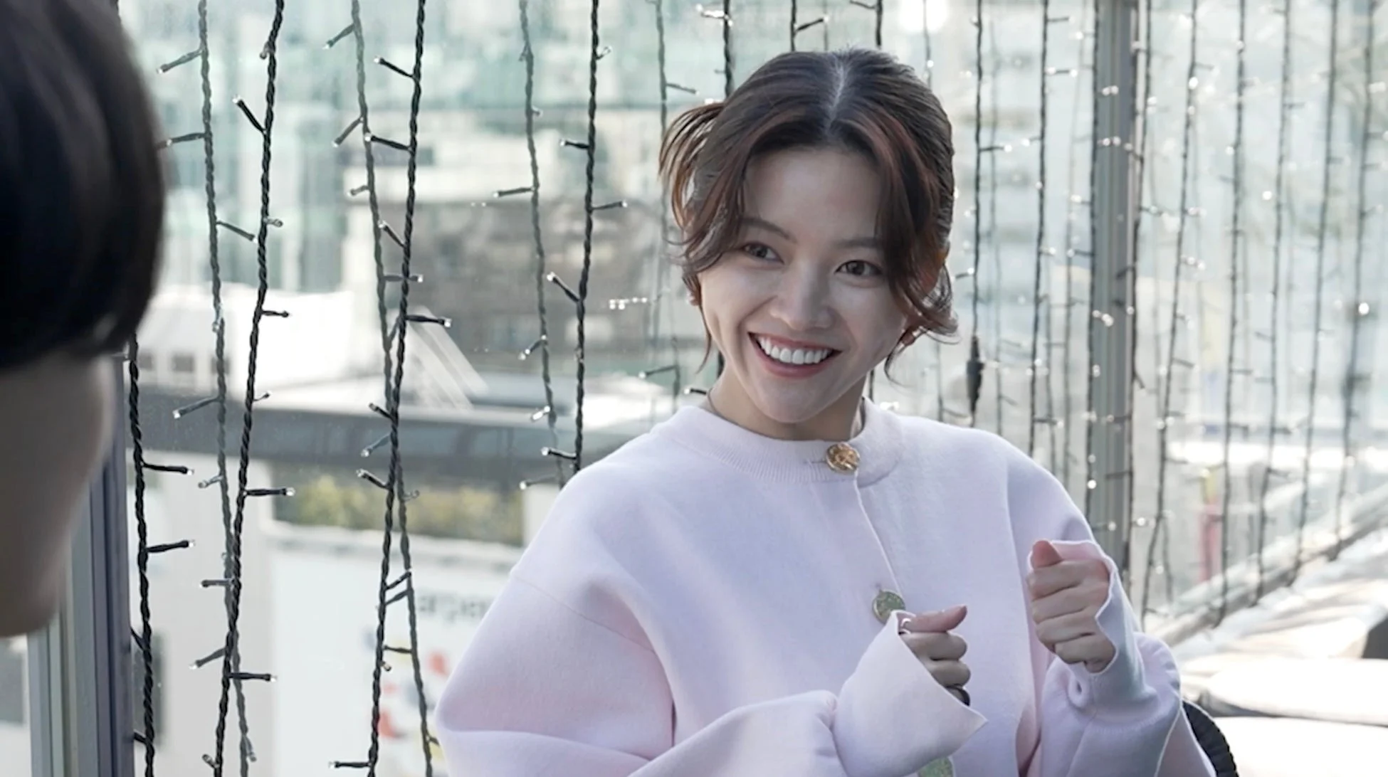 ピンク色の服を着て笑顔を見せる女性