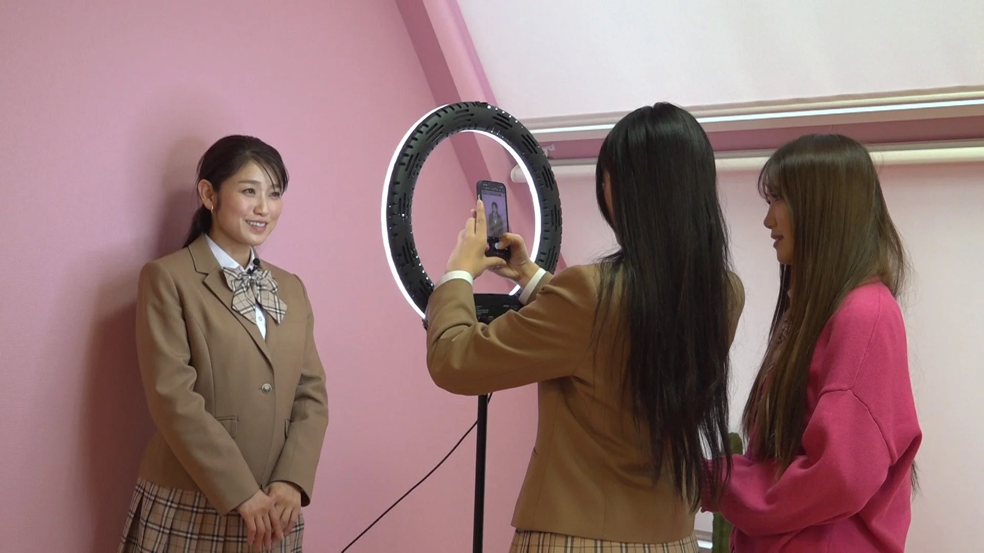 リングライトを使ってスマホで撮影する制服の女性たち