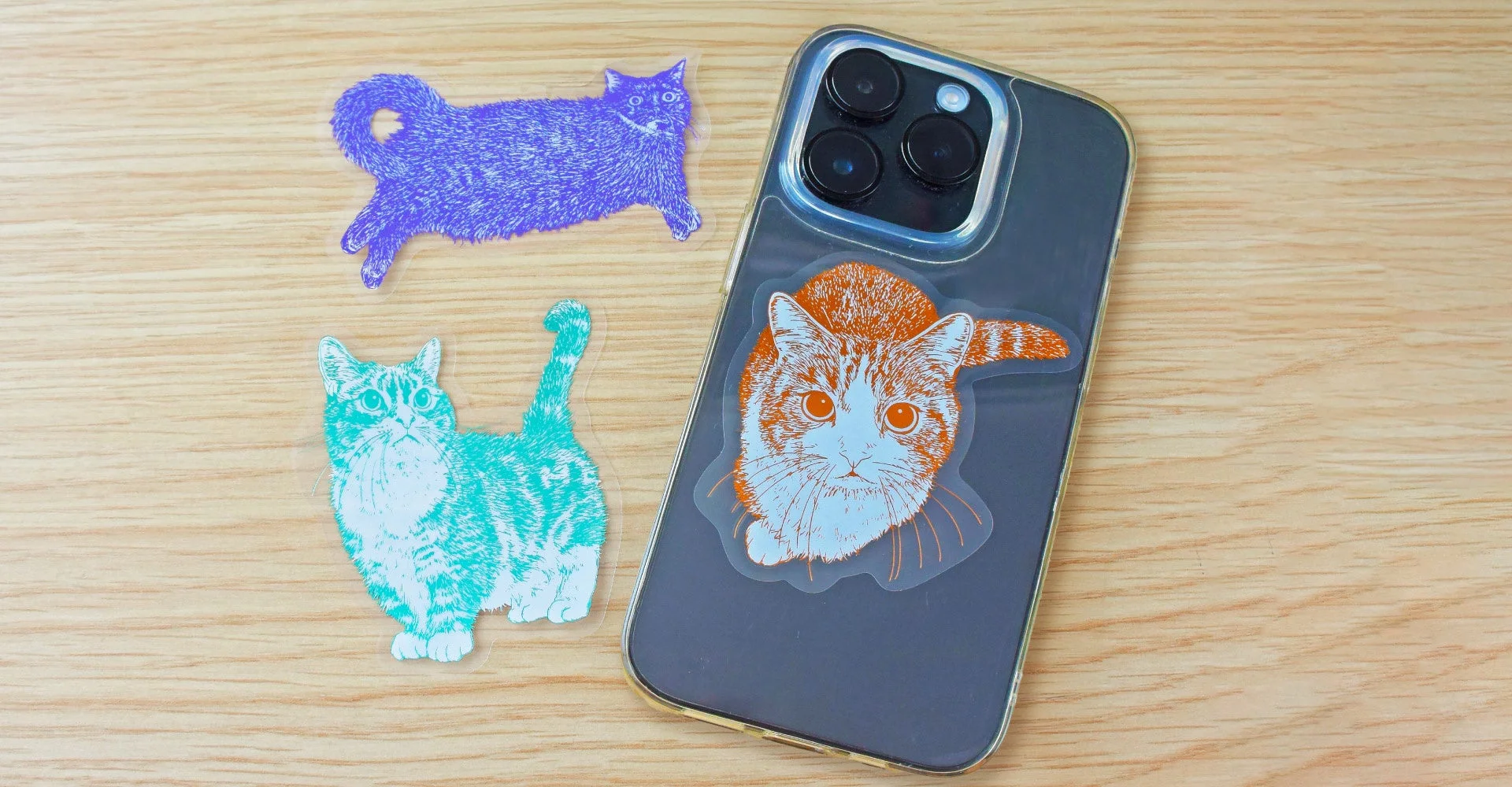 木目のテーブルに置かれたiPhoneと猫のステッカーのクローズアップ
