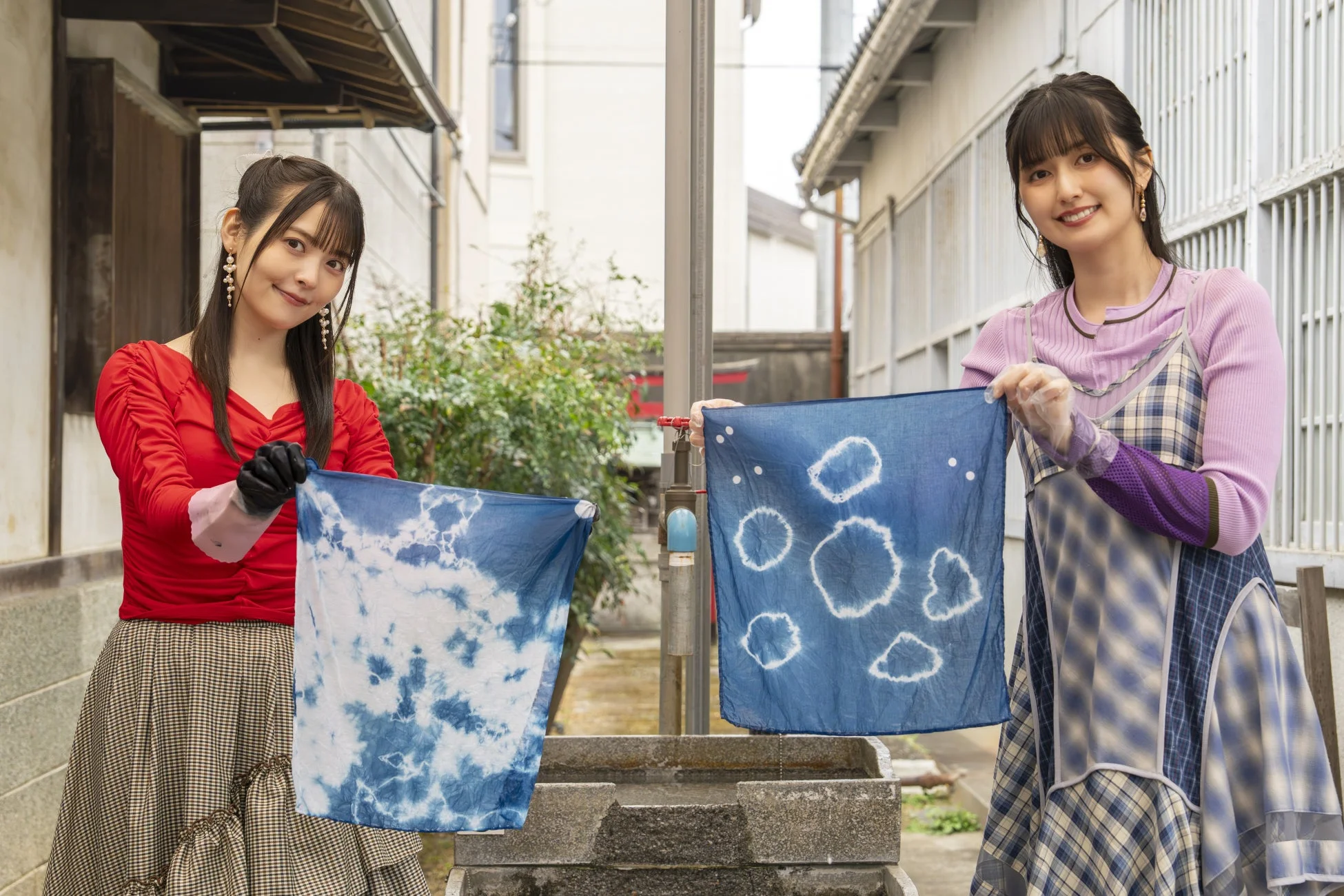 二人の女性が藍染めの布を披露