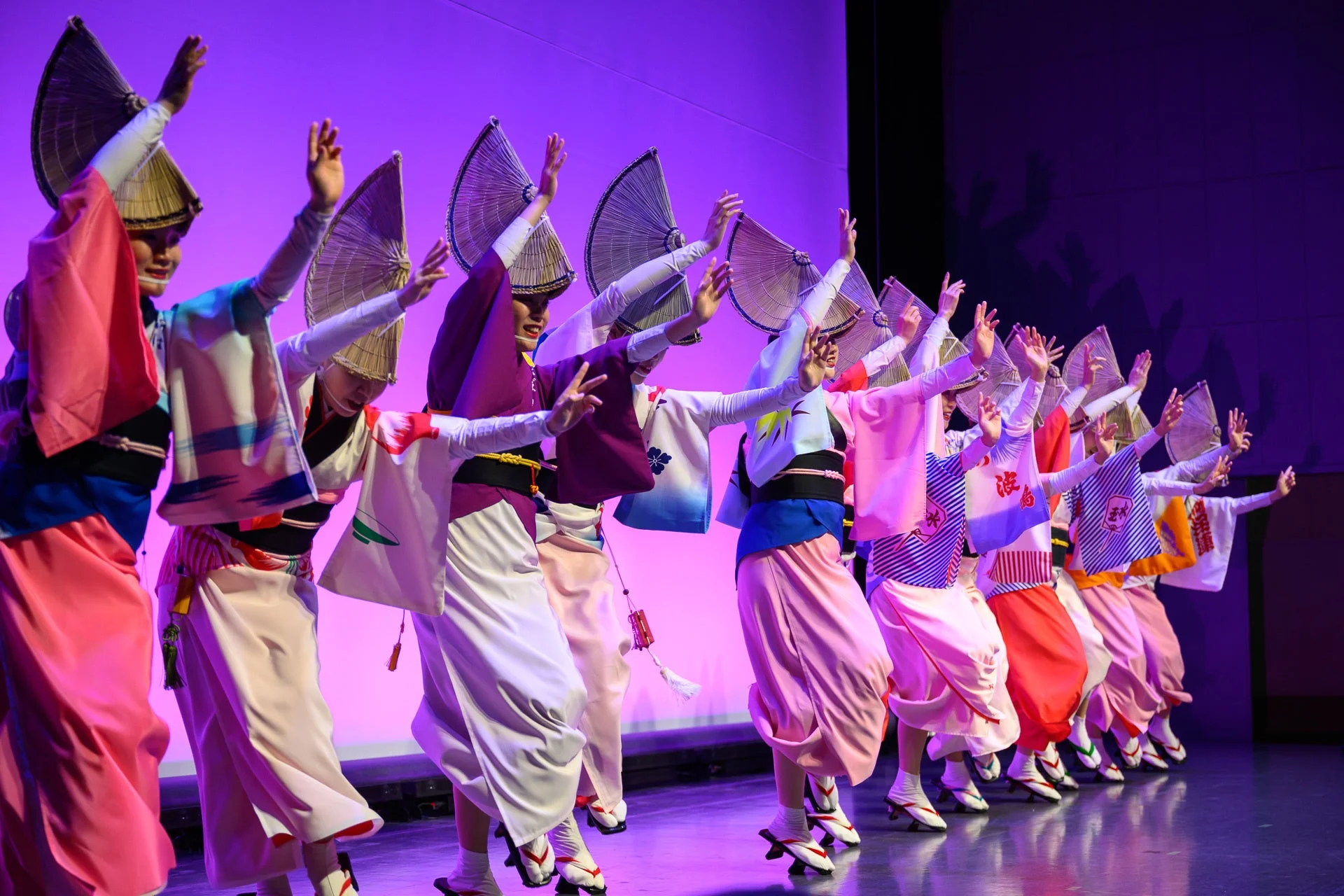 紫色の背景のステージで踊る阿波踊りの人々
