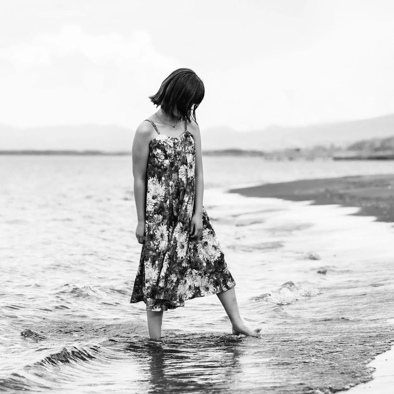 水辺に立つ女性のモノクロ写真