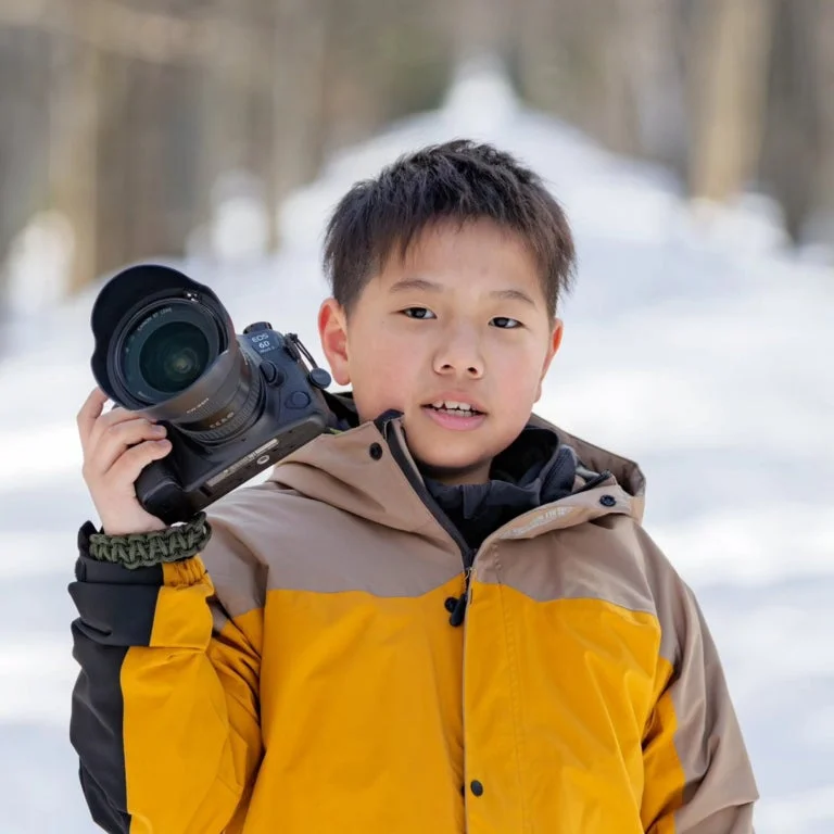 雪景色の中でカメラを構える少年