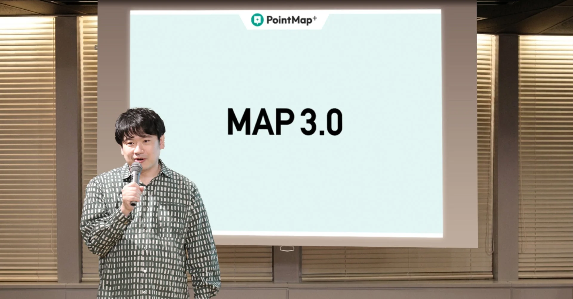 男性がマイクを持ってプレゼンテーションを行っている様子