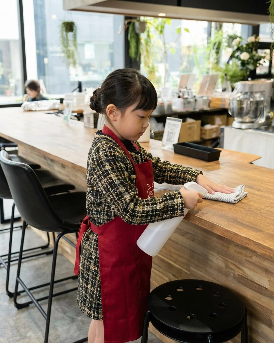 赤いエプロンをつけた女の子がカウンターを拭く様子
