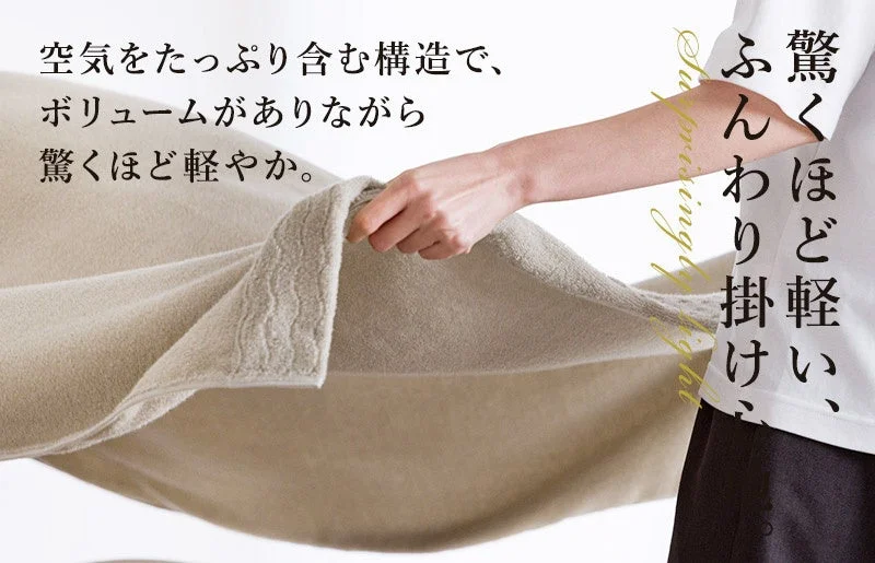 軽やかな肌触りのベージュ色のタオルまたはブランケットが写っています。空気を多く含む構造で、ボリュームがありながらも驚くほど軽いという特徴が強調されており、そのふんわりとした質感が伝えられています。