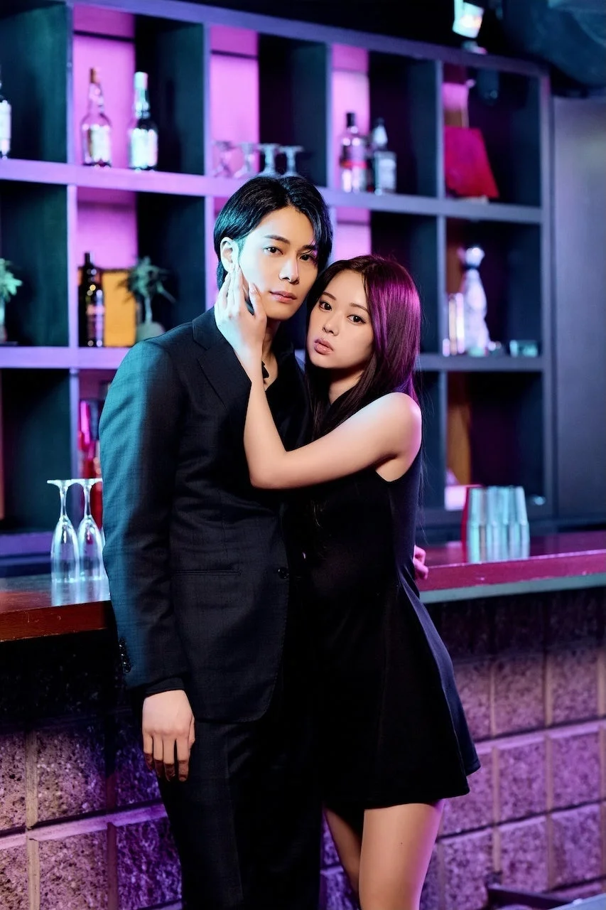 紫の照明のバーで寄り添う男女