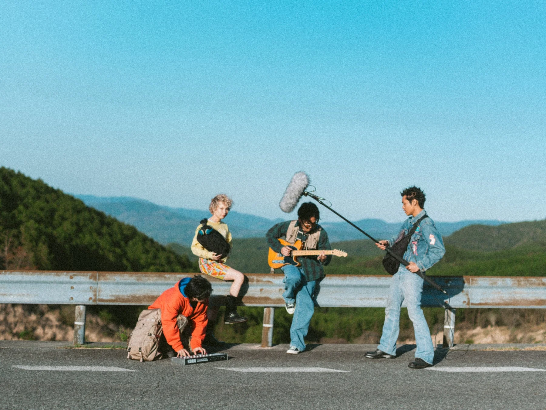 山々を背景にしたロードサイドで、音楽活動を楽しむ若者たち