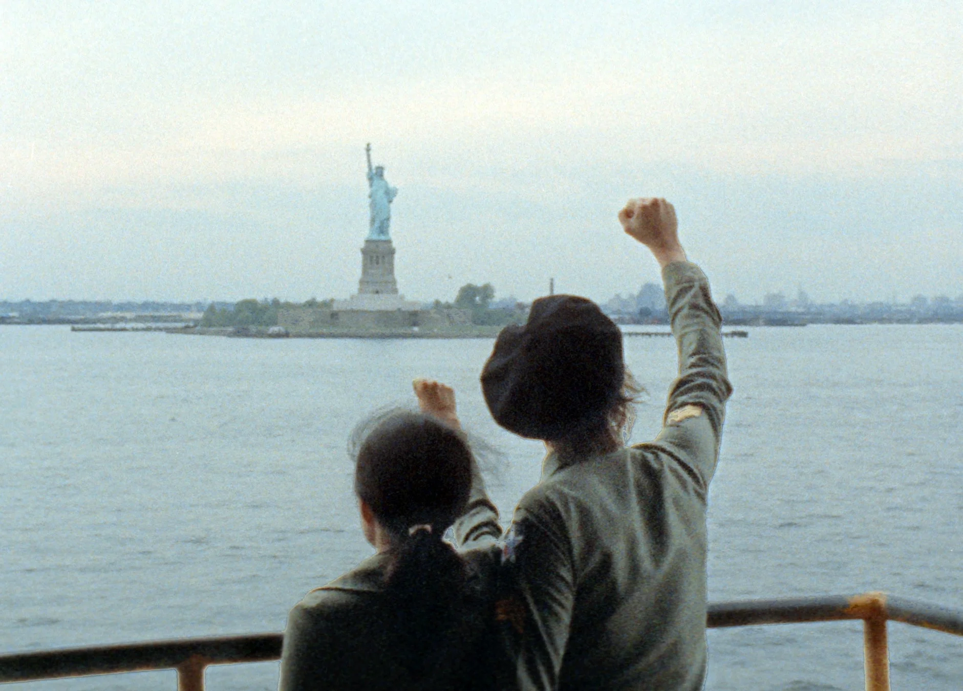 自由の女神像を背景に拳を掲げる二人