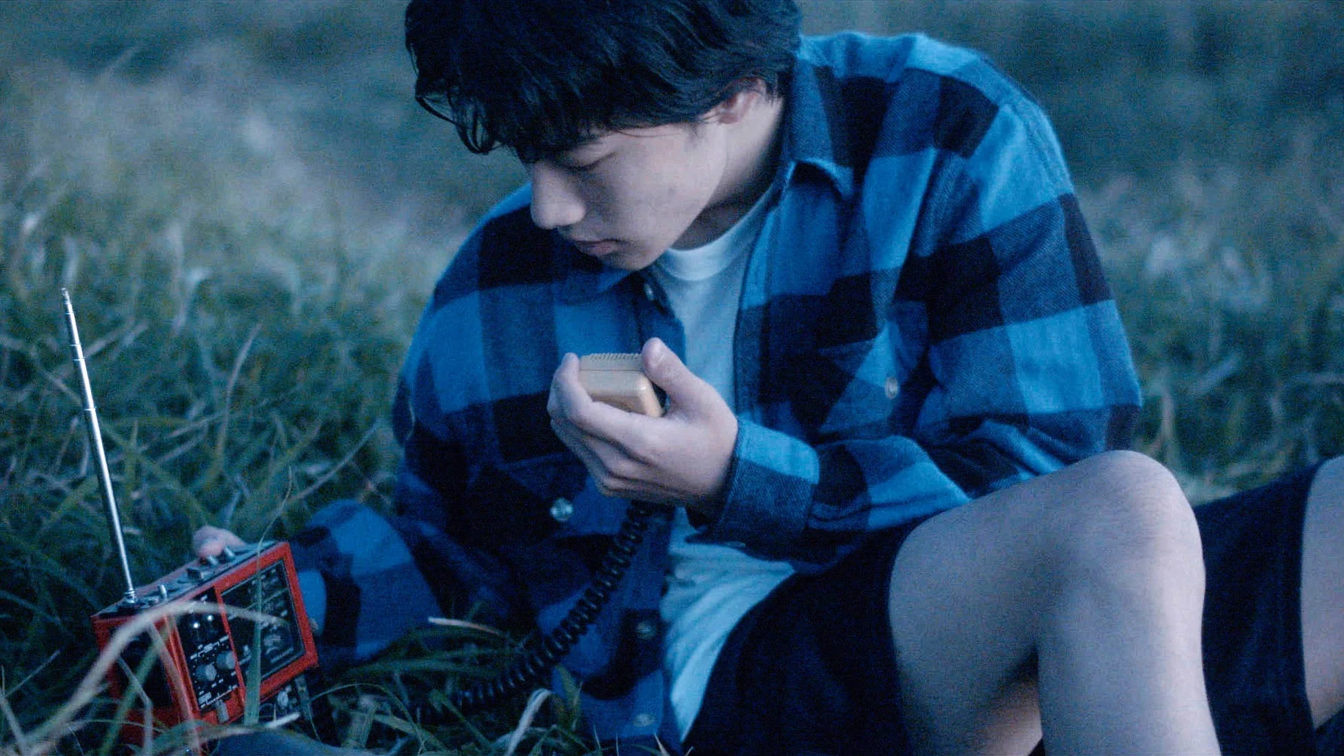 草むらでラジオを操作する男性