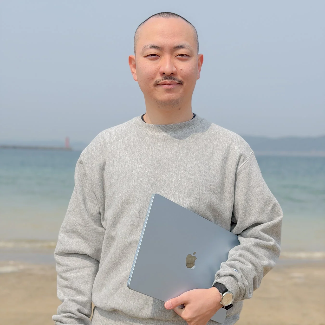 ビーチでノートパソコンを抱える中村氏