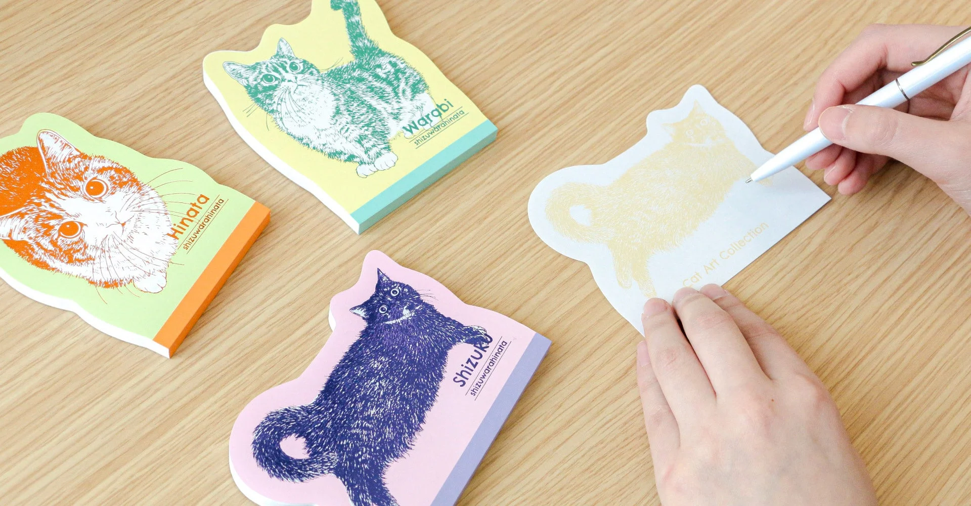 猫のイラストが描かれたカラフルな付箋に書き込みをする手の様子