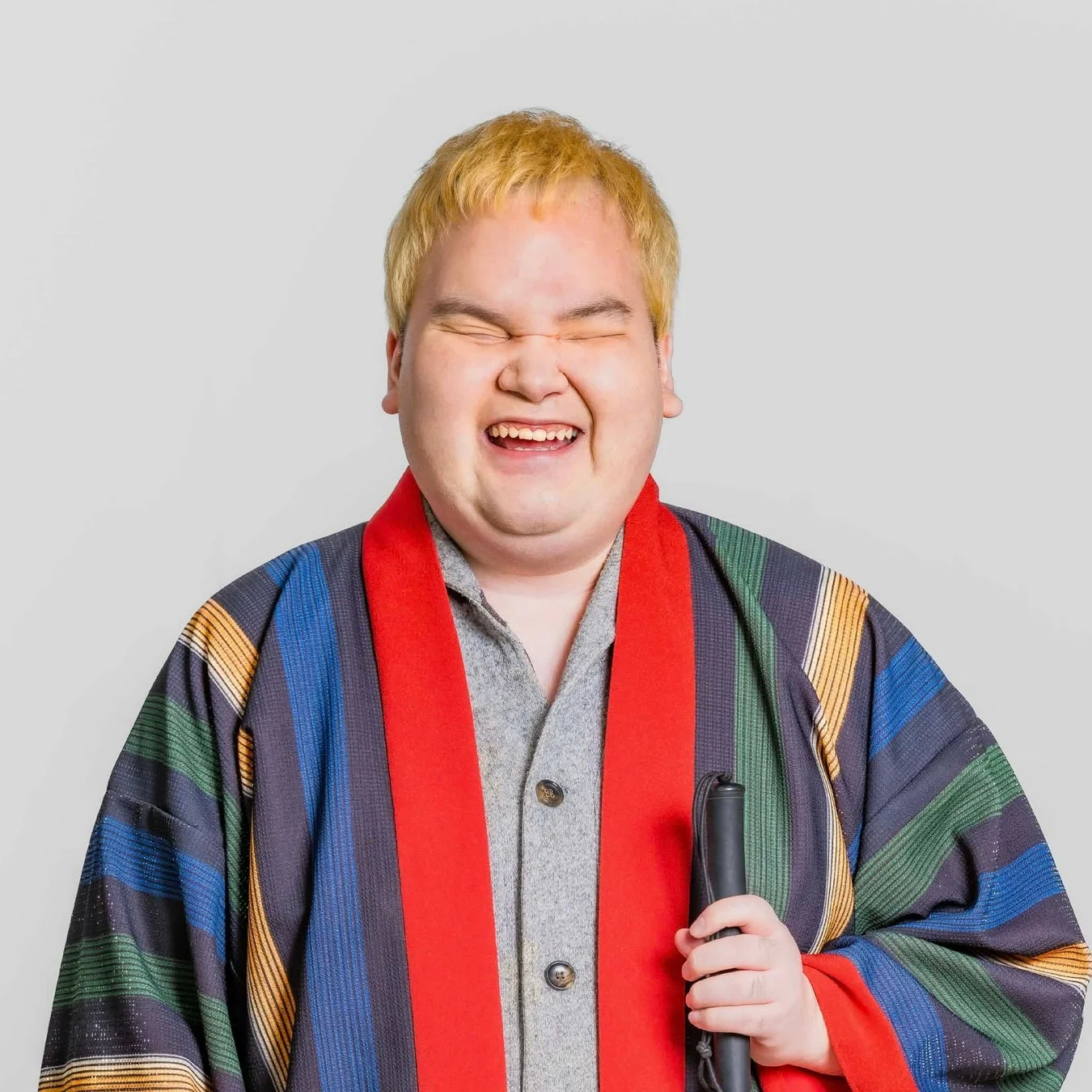 金髪の男性が笑顔で目を閉じるポートレート