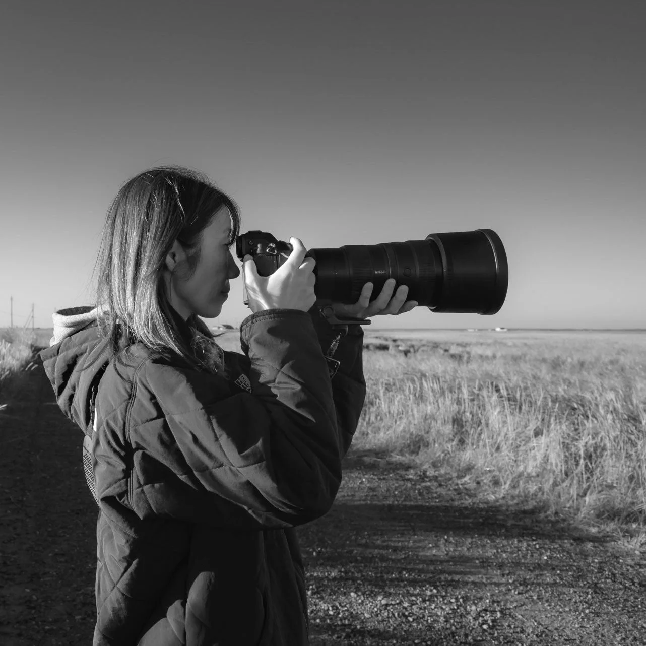 カメラを構える女性写真家のモノクロ写真