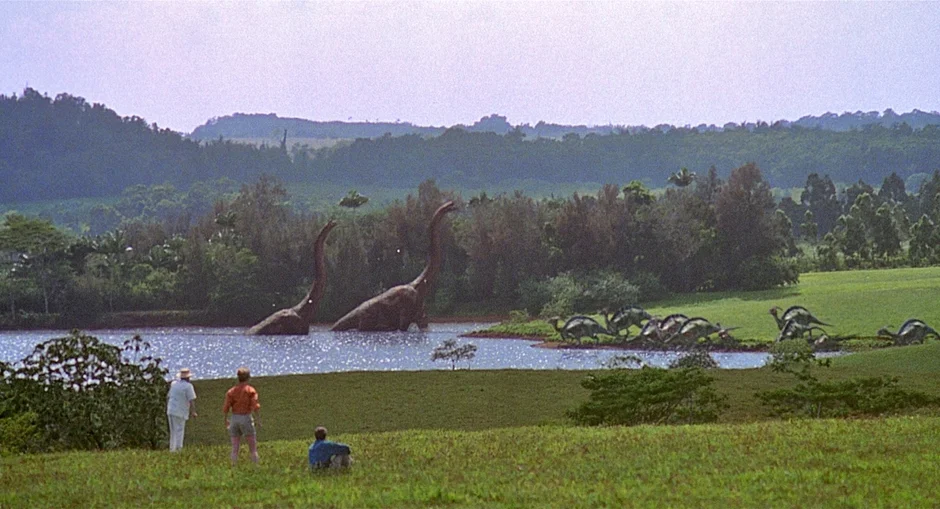 恐竜と人物が湖畔に立つシーン