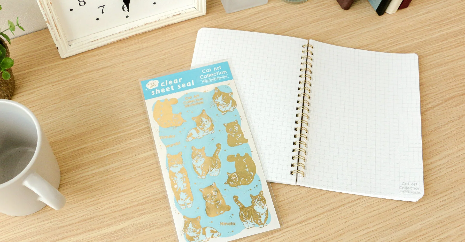開かれた方眼ノートと金色の猫のイラストが描かれたクリアシートシール