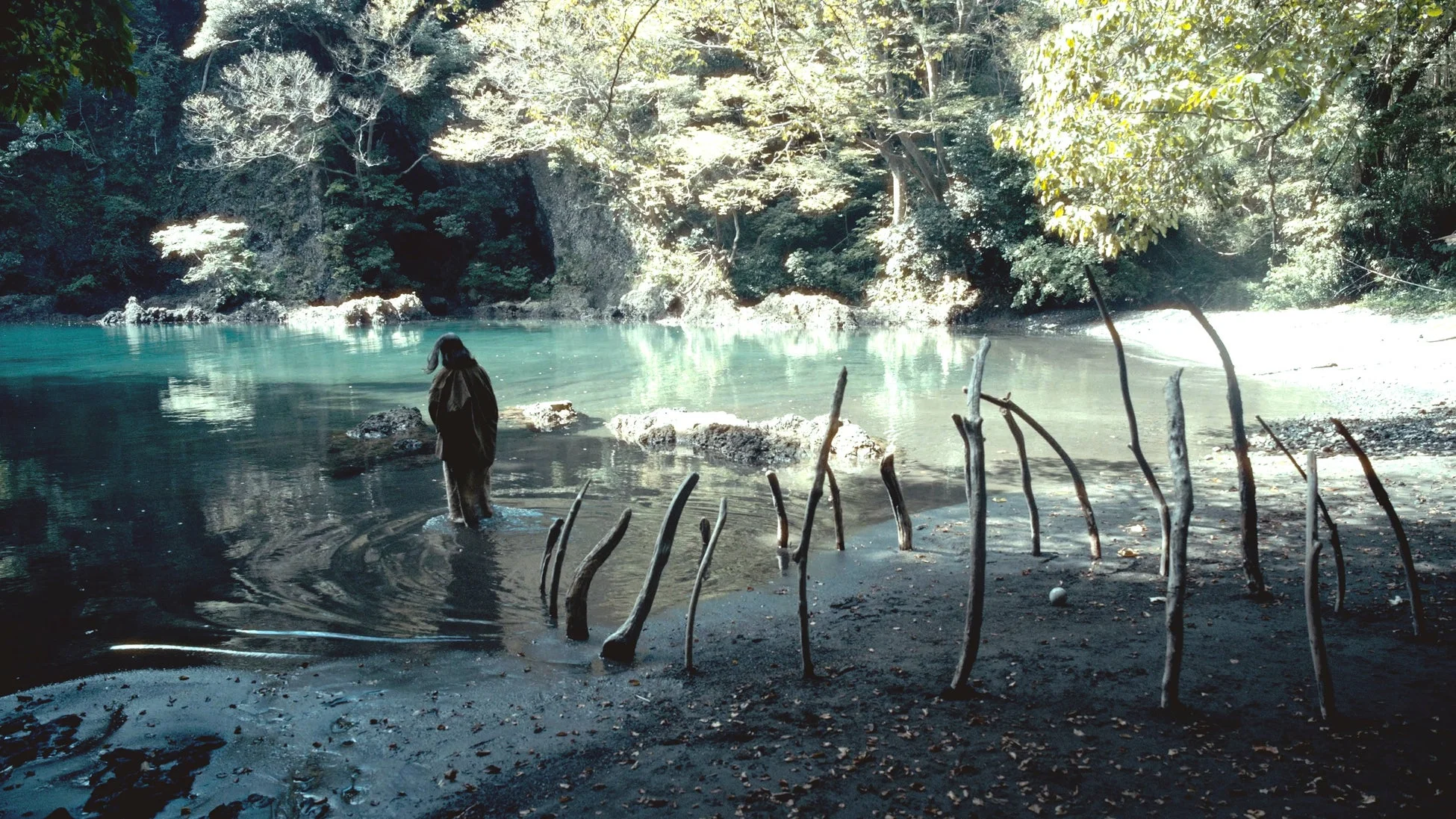 水辺に立つ人物と木の棒