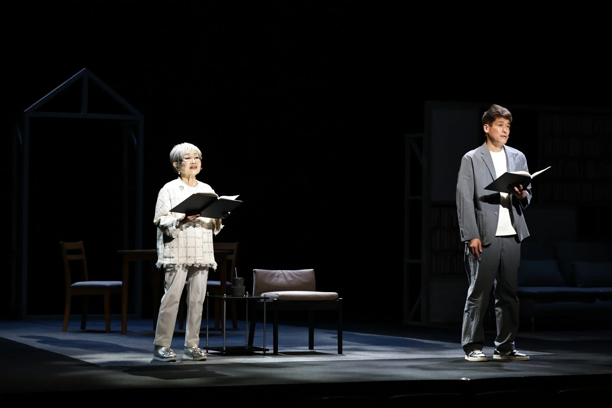 舞台上で本を手に立つ男女二人