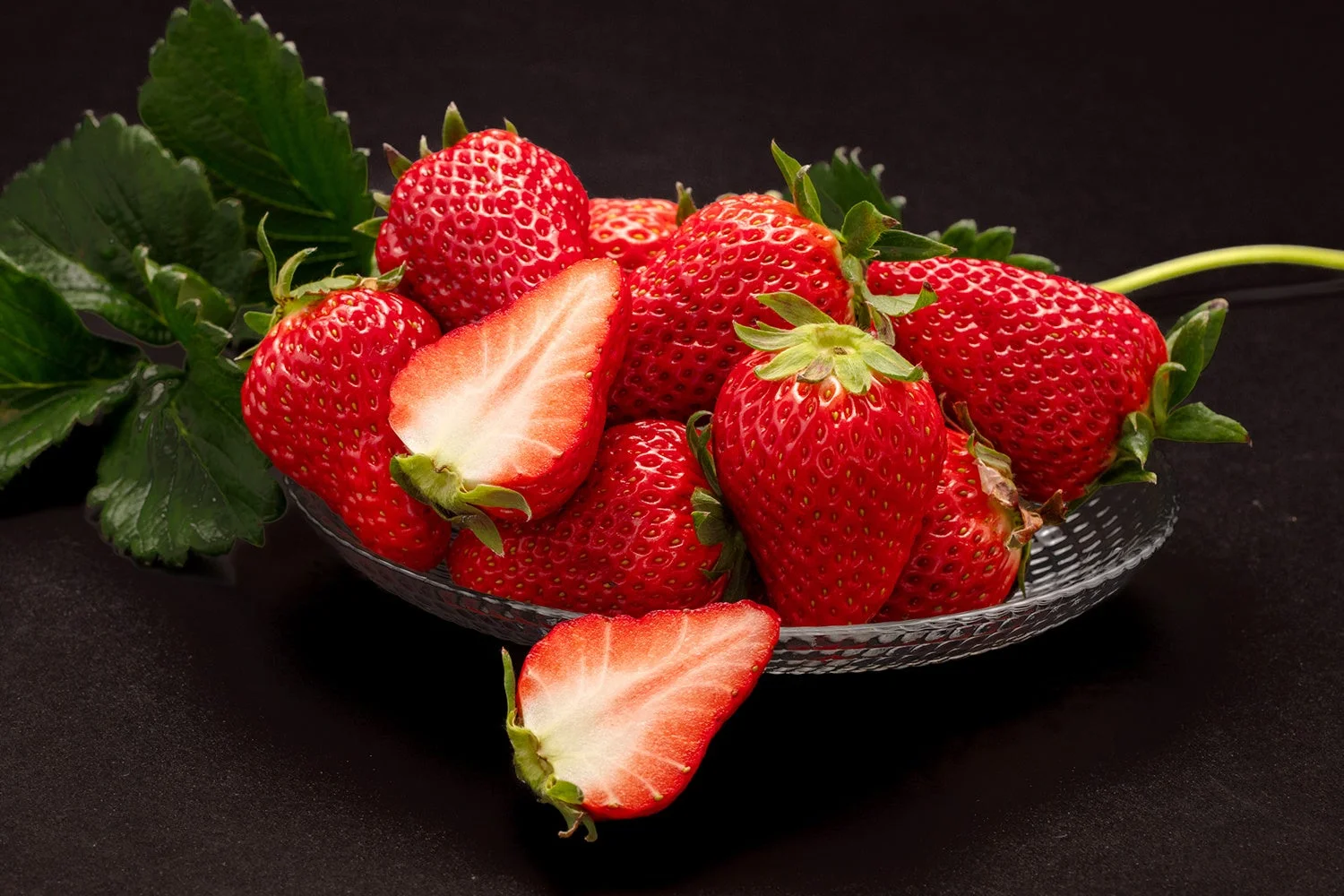 黒い背景に盛られたたくさんの真っ赤ないちご