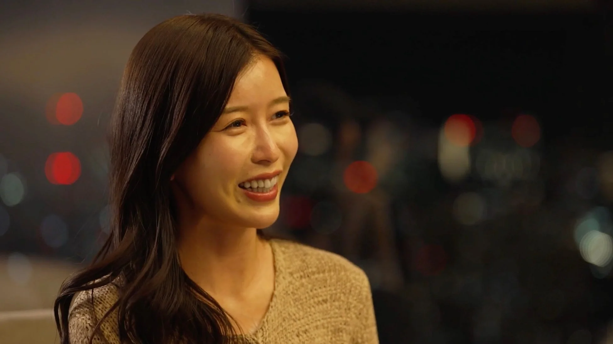 夜景を背景に笑顔を見せる若い女性