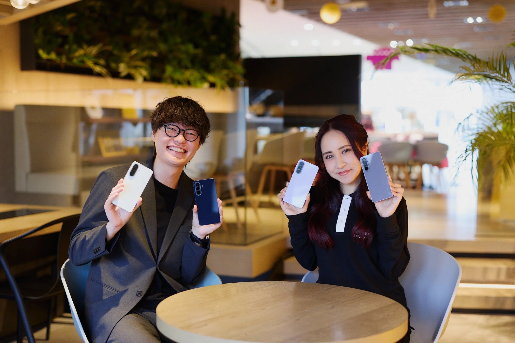 カフェでスマートフォンを手に笑顔の男女