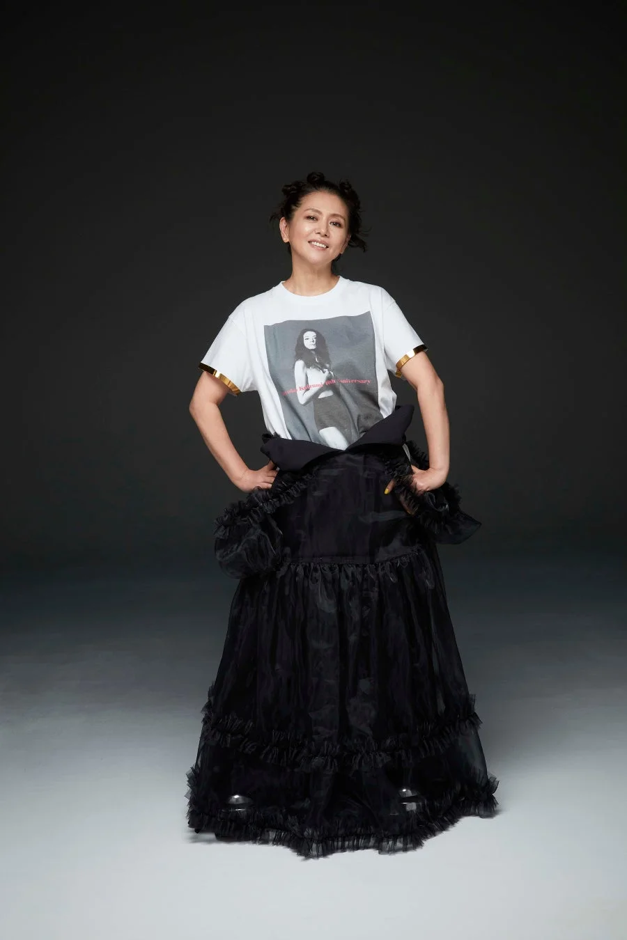 白いTシャツとボリュームのある黒いフリルスカートを着用した女性