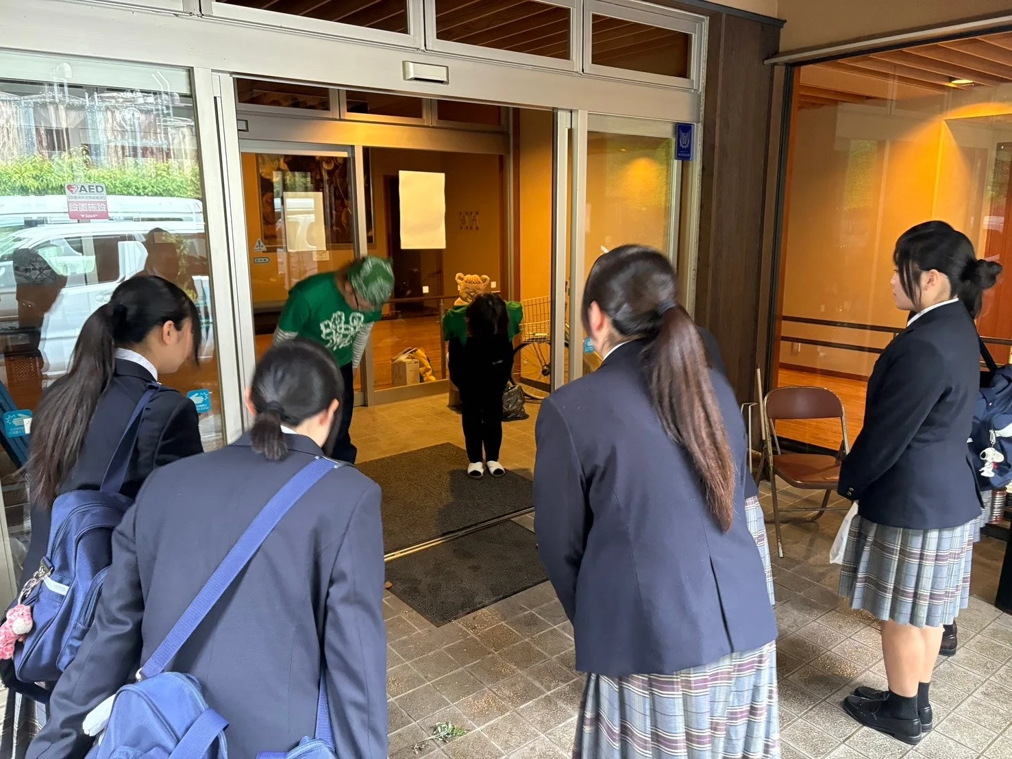 制服姿の女子学生が建物の入り口に立つ様子