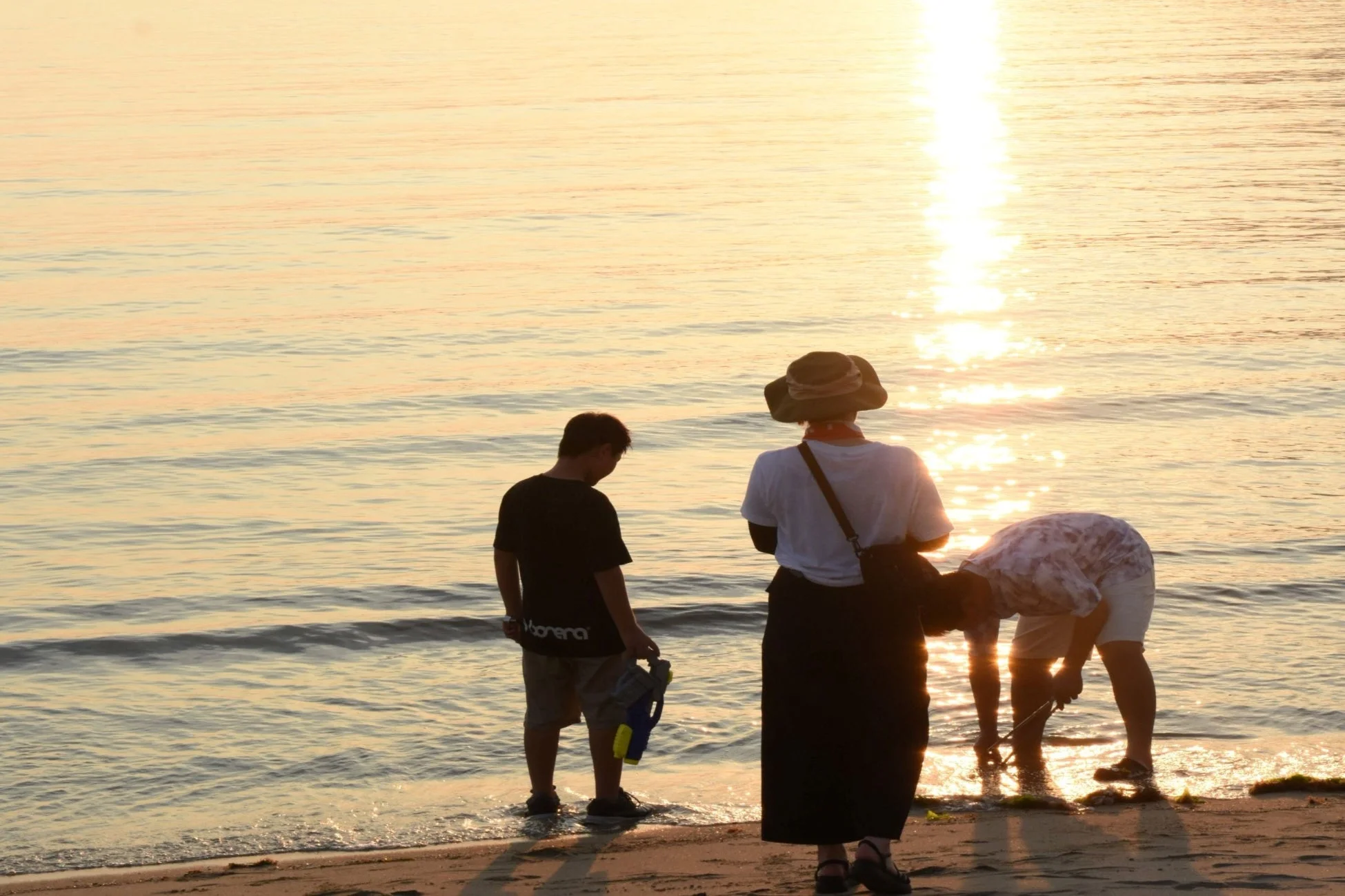 夕暮れの海辺で遊ぶ家族