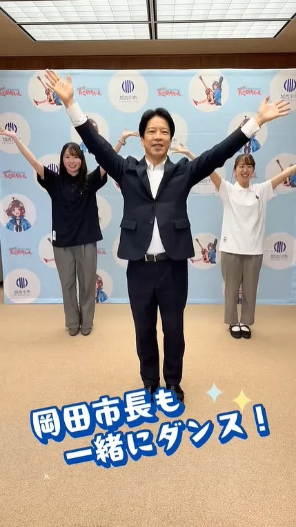岡田市長が二人の女性と共に笑顔でダンスをする様子