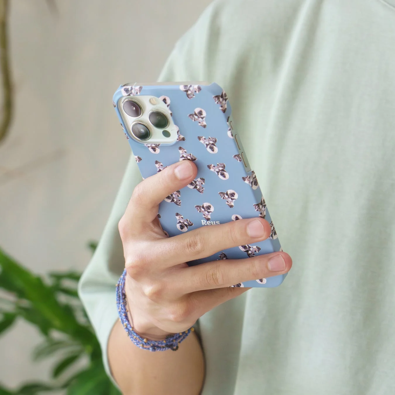 フレンチブルドッグ柄のスマホケースを装着したiPhoneを持つ手元