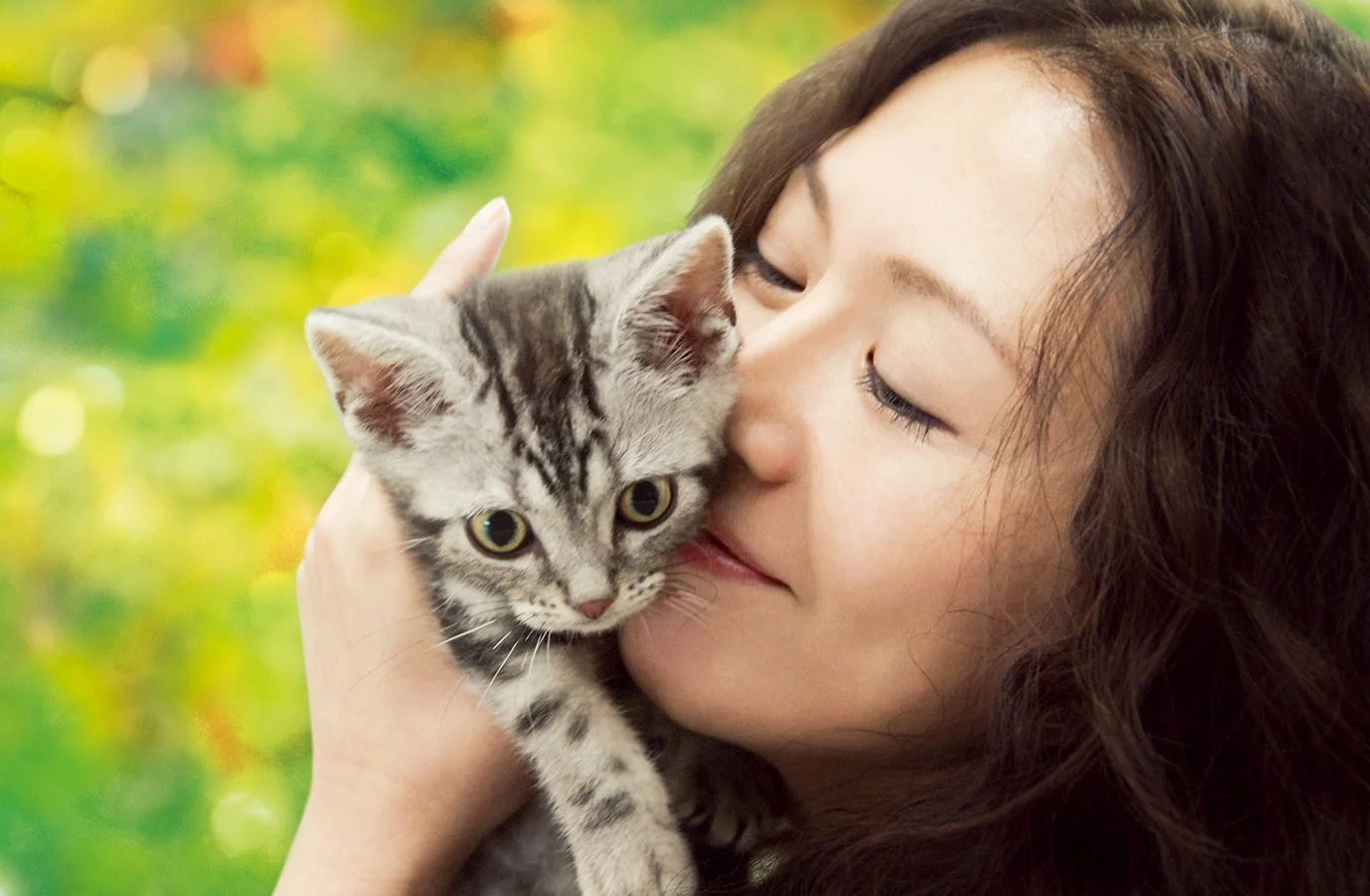 一人の女性が愛おしそうに子猫を抱きしめている
