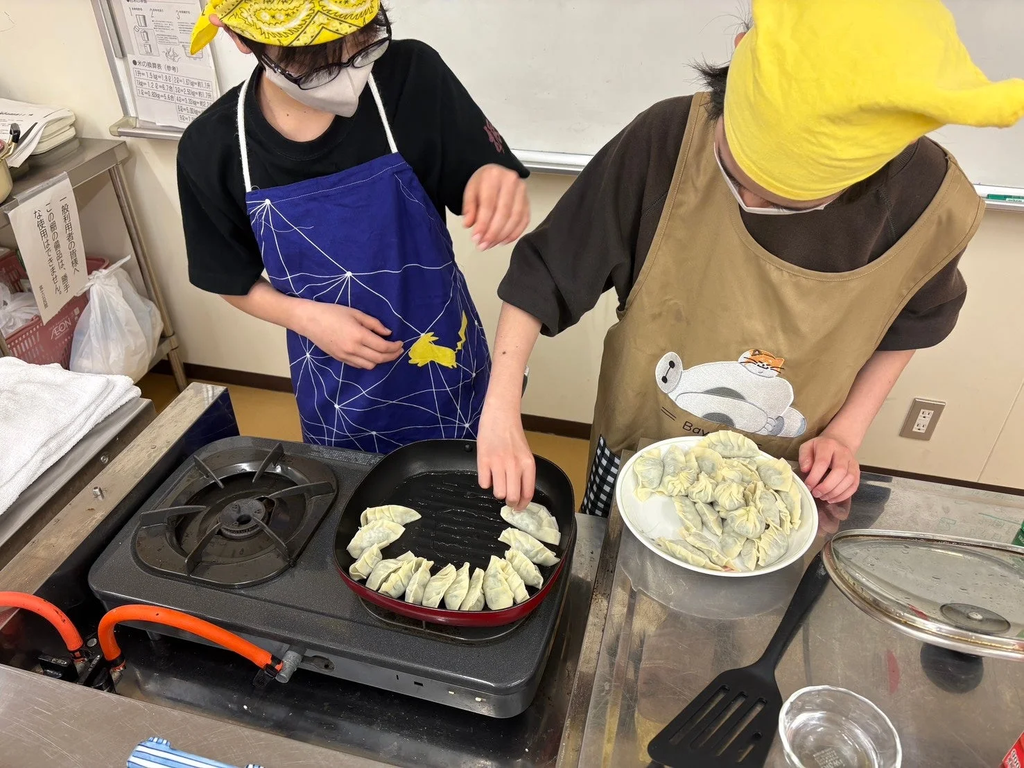 二人の人物がキッチンで餃子を焼いている様子