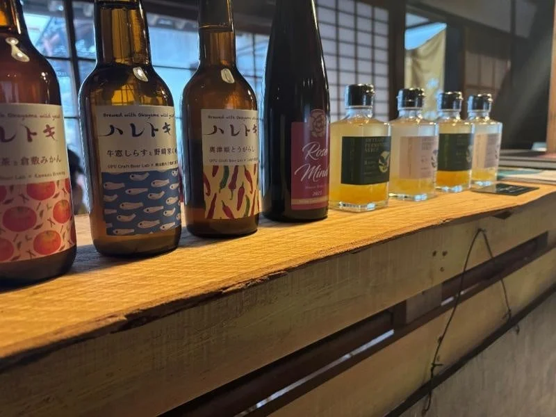 木製のカウンターに、クラフトビール「ハレトケ」のボトル3種類、赤ワイン、そして小瓶のリキュールが整然と並べられています。和風の店内で、様々な種類の酒が展示されている様子がうかがえます。