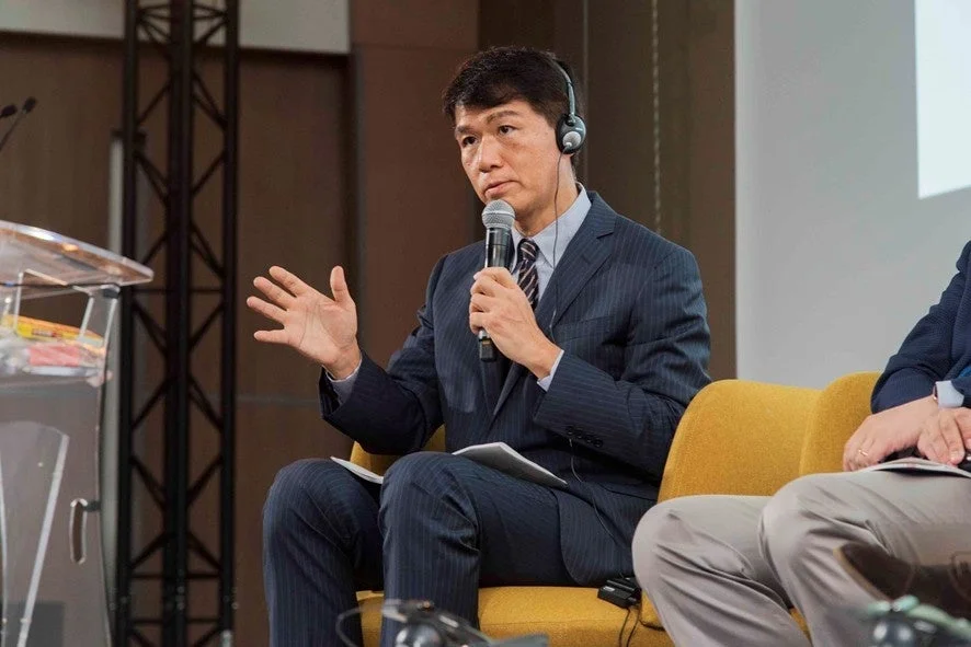 スーツを着た井上岳久氏が講演中