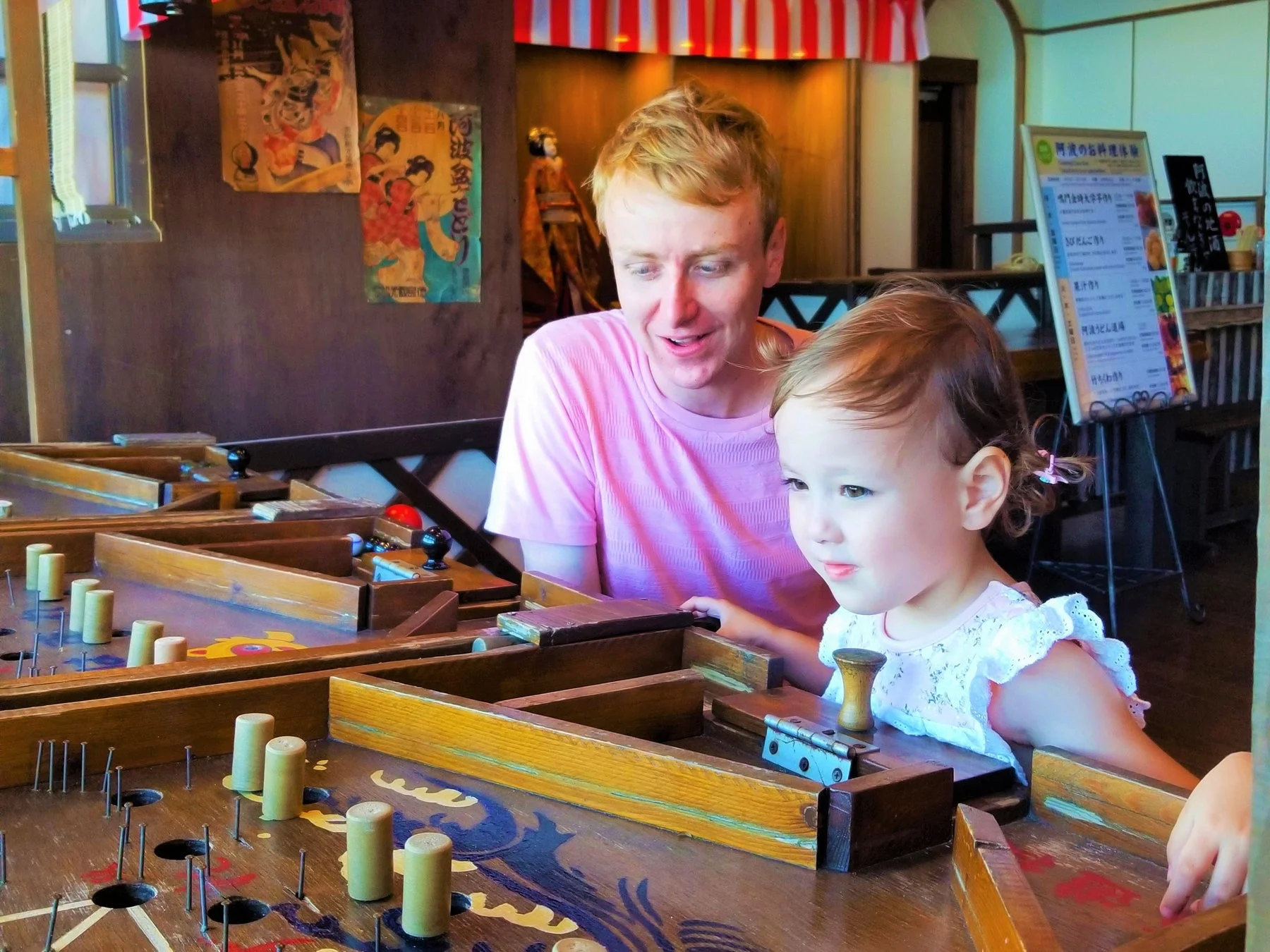 父親と子供が伝統的な木製ゲームで遊ぶ様子