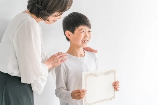 母親と男の子が賞状を持って喜ぶ様子