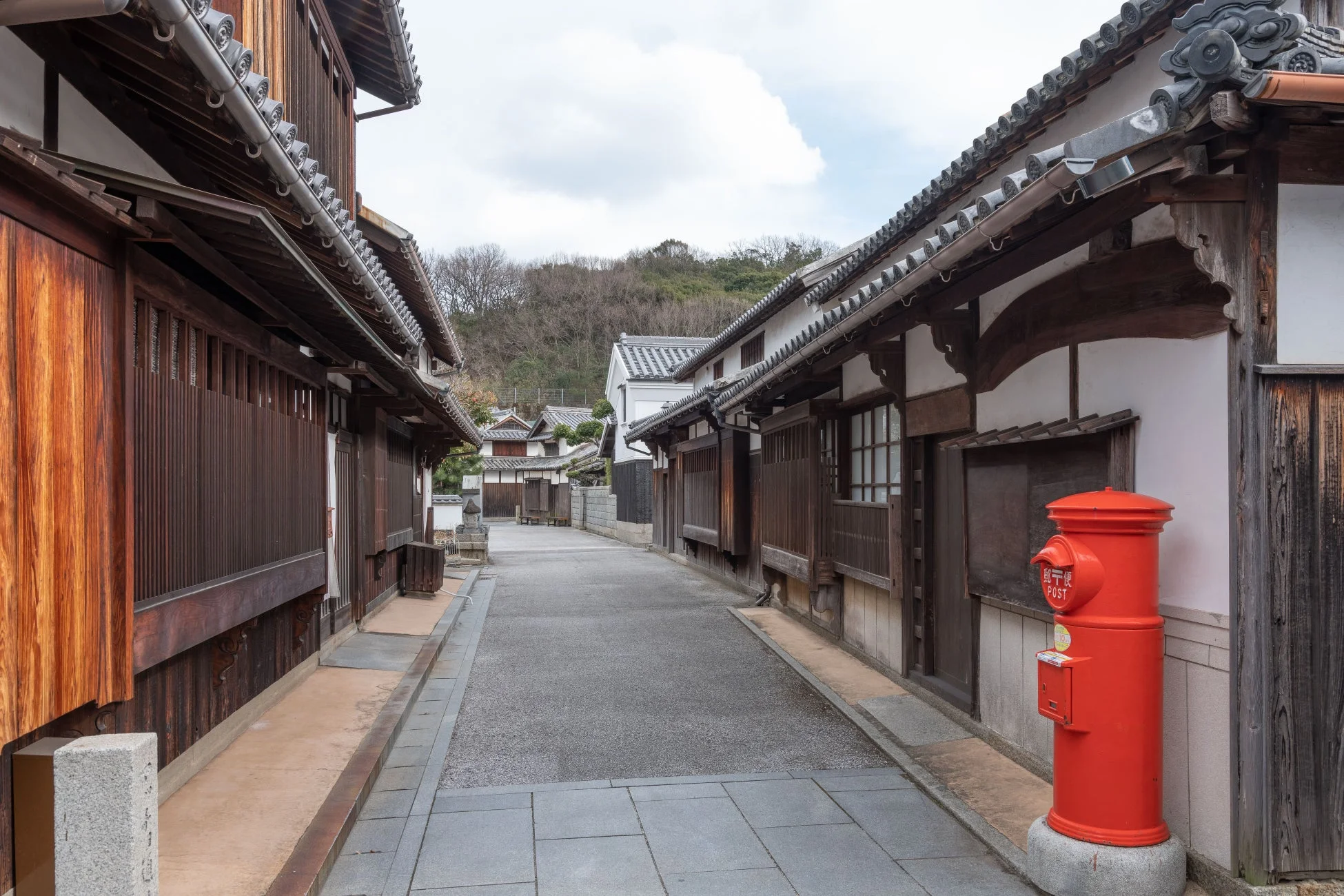 伝統的な木造家屋と赤い丸型ポストが印象的な路地