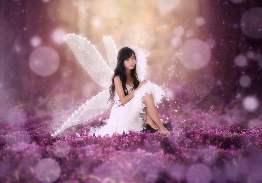 妖精のような女性が花畑に座る幻想的な写真