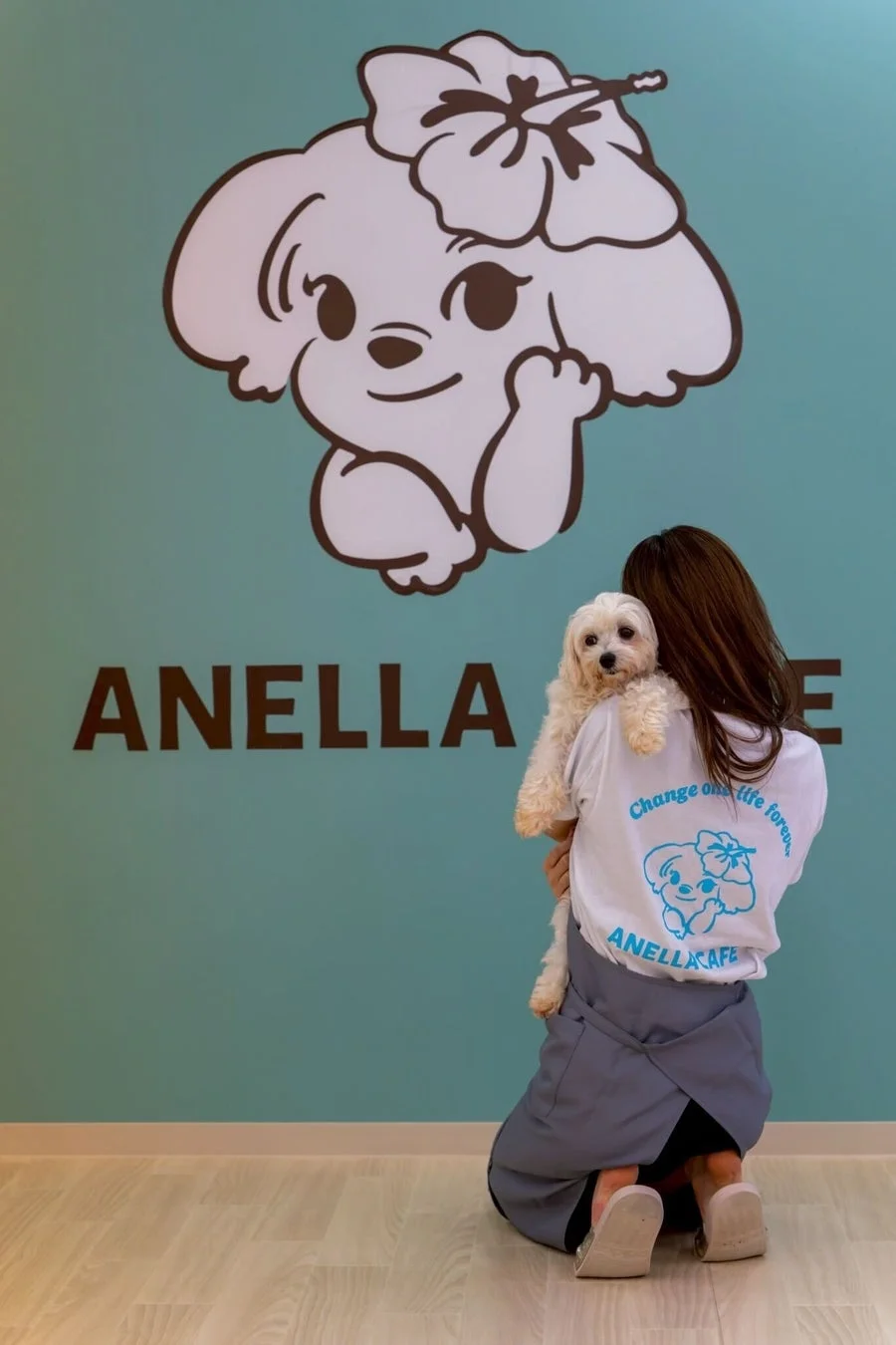 女性が白い小型犬を抱きかかえる様子