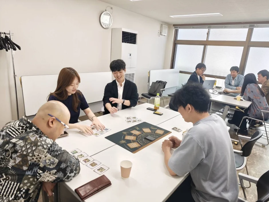 オフィスのような部屋で、複数の人々がテーブルを囲んでいます