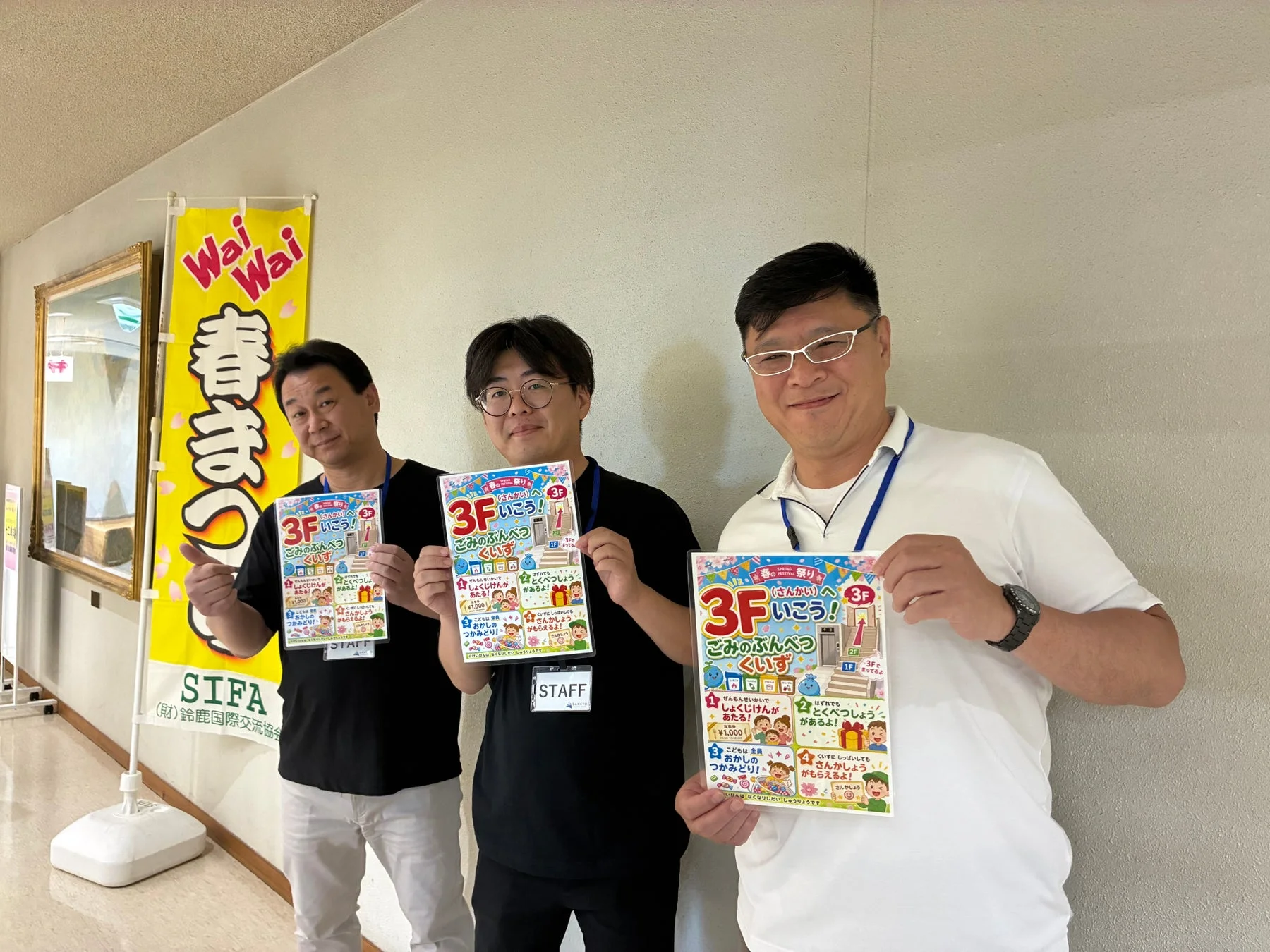 春まつりとゴミ分別クイズのポスターを持つ男性たち。