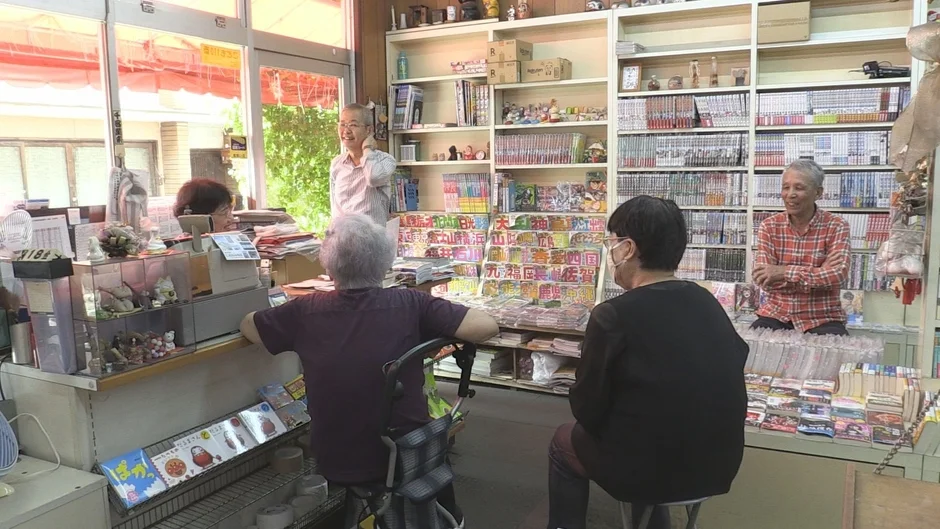 多くの本や雑誌が並ぶ昔ながらの書店で、数人の高齢者が談笑している様子です。