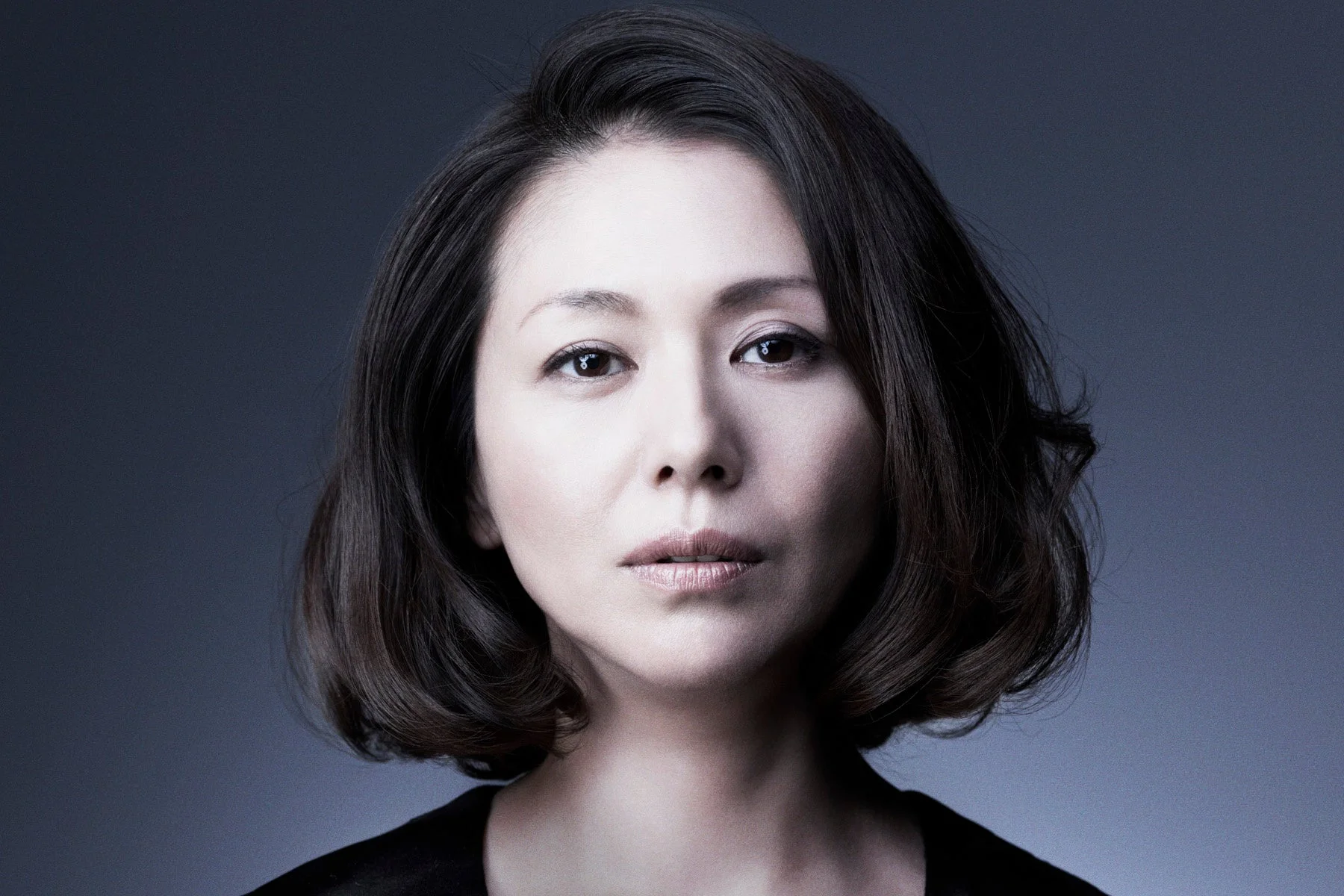暗い背景を背に、カメラをまっすぐ見つめるショートヘアの日本人女性のポートレート