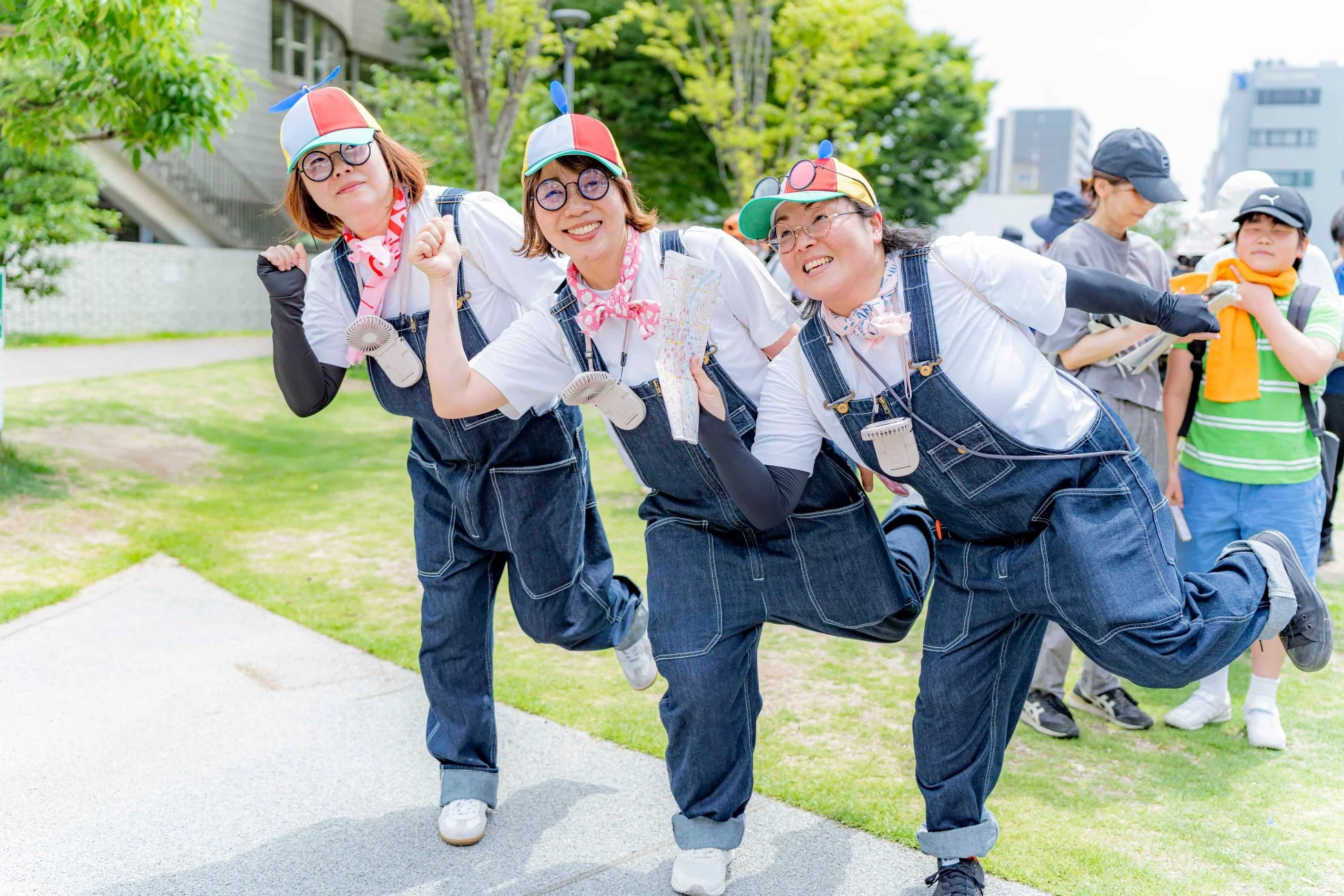お揃いのデニムオーバーオールとプロペラ帽を身につけた3人の女性