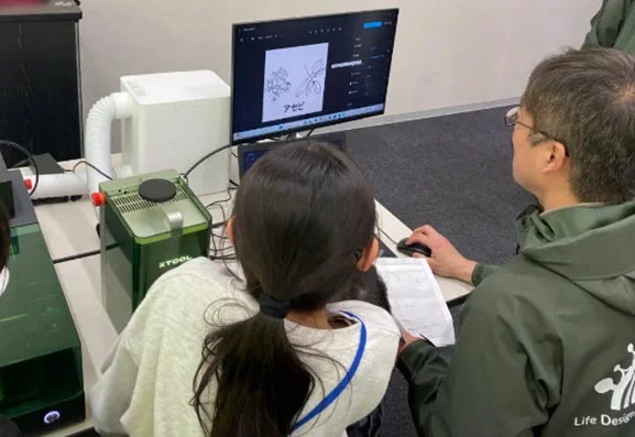レーザー加工機を使用する子どもと大人