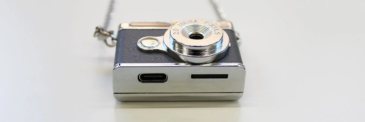 チェーンが付いた小型のレトロなデザインのデジタルカメラが写っています。