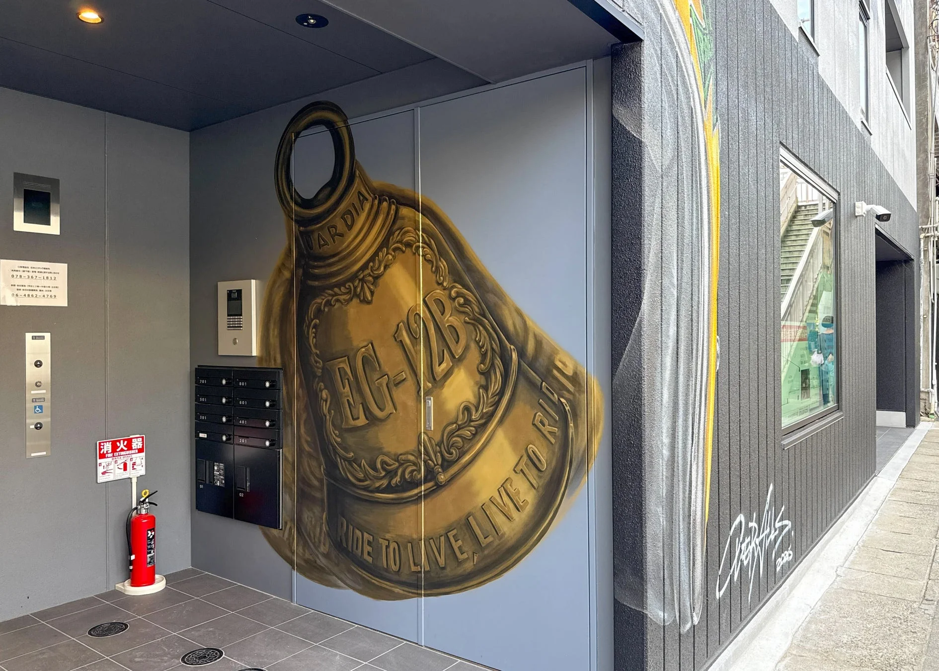 建物のエントランスに描かれた、金色に輝く大きなベルかヘルメットのような壁画